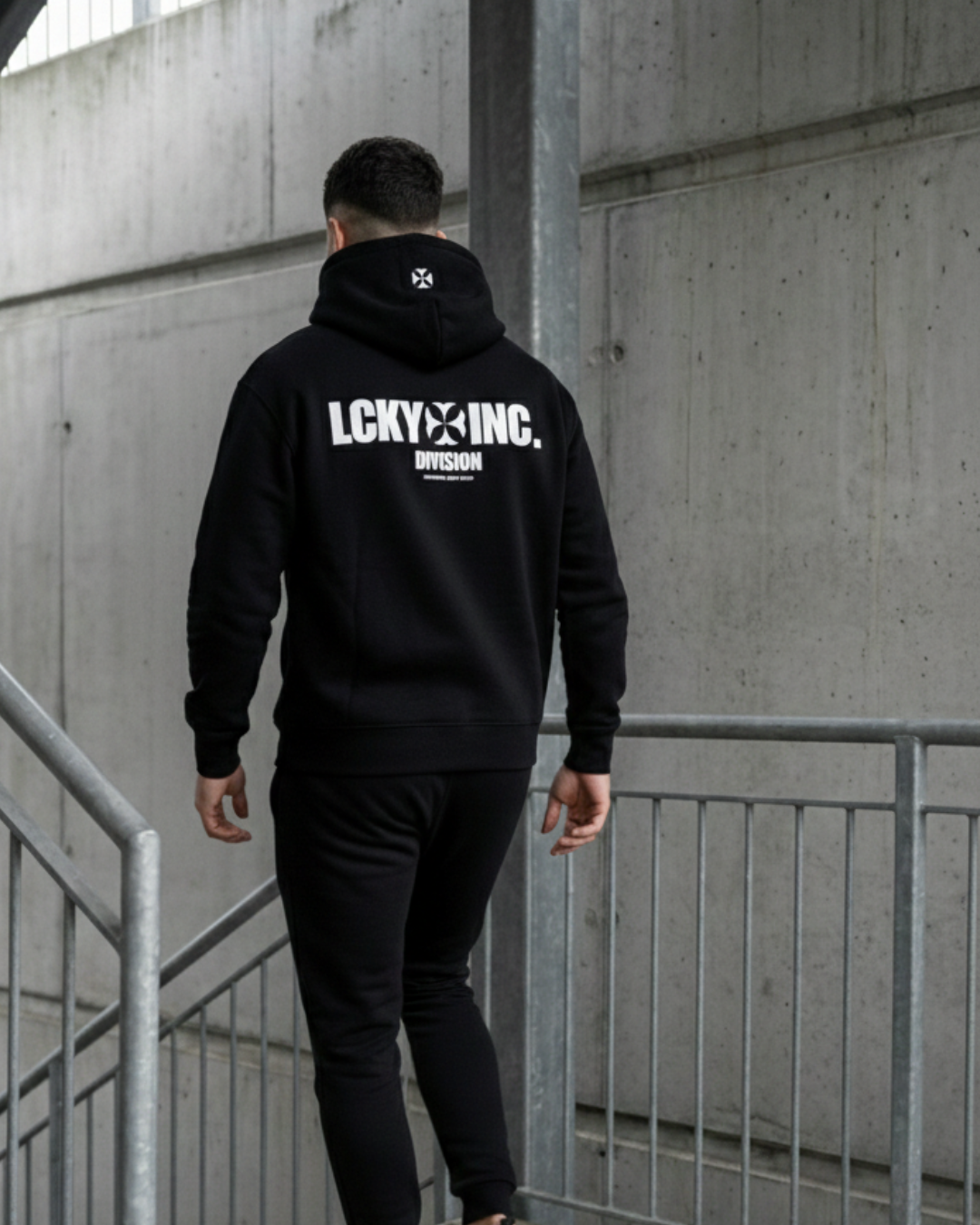 A man in a black LCKY INC hoodie walks downstairs